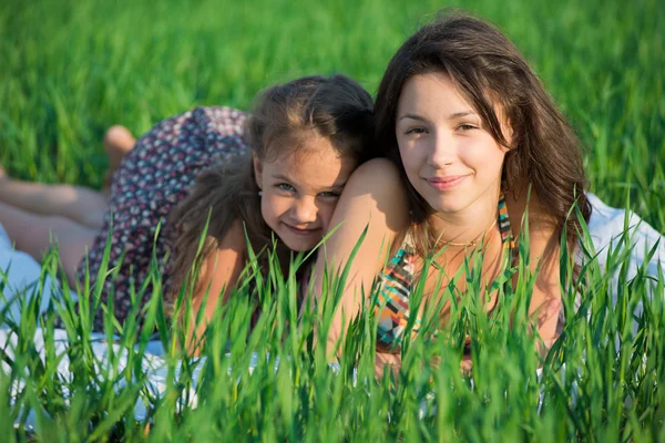 Happy girls lying on green grass — Stock Photo, Image