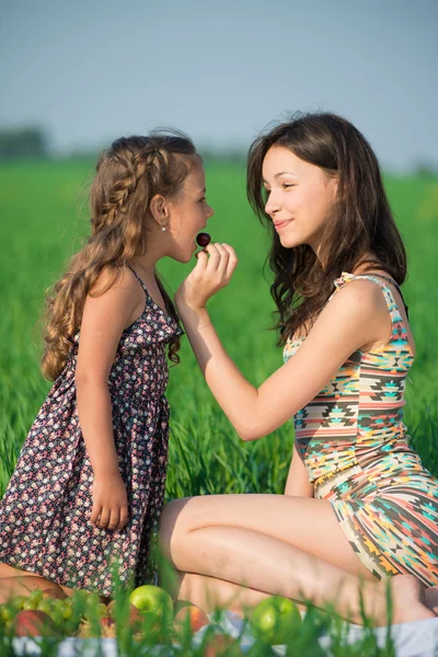 Girls eating cherry fruit at picnic — Stock Photo, Image