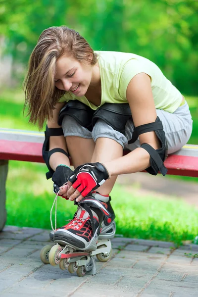 Girl putting on inline skates on bench — Stock Photo, Image