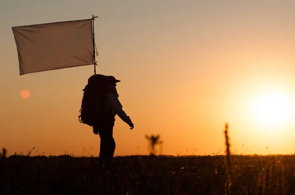 Hiker with backpack and flag in field — Stock Photo, Image