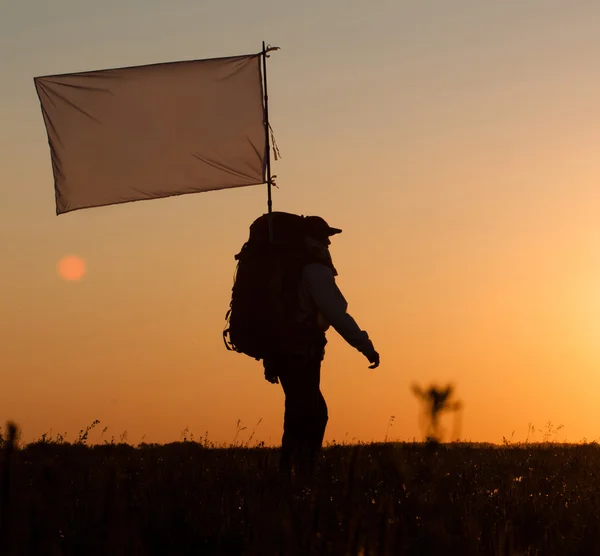 Wandelaar met rugzak en vlag in veld — Stockfoto