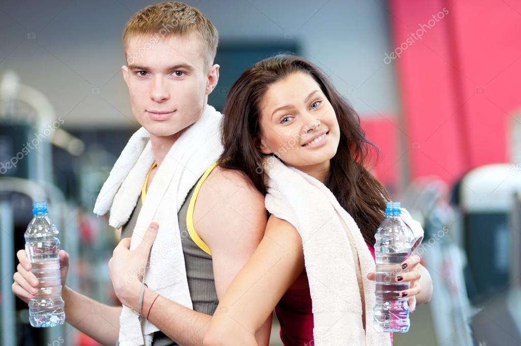 Man and woman drinking water in gym