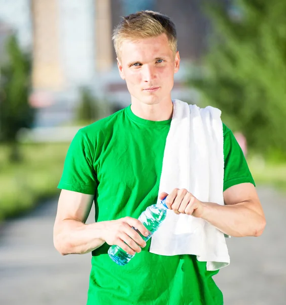 Beyaz havlu içme suyu plastik bir şişe ile yorgun adam — Stok fotoğraf