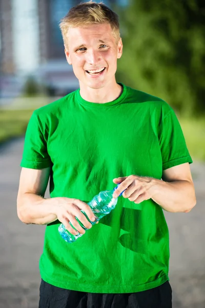 Trött man dricksvatten från en plastflaska efter fitness — Stockfoto