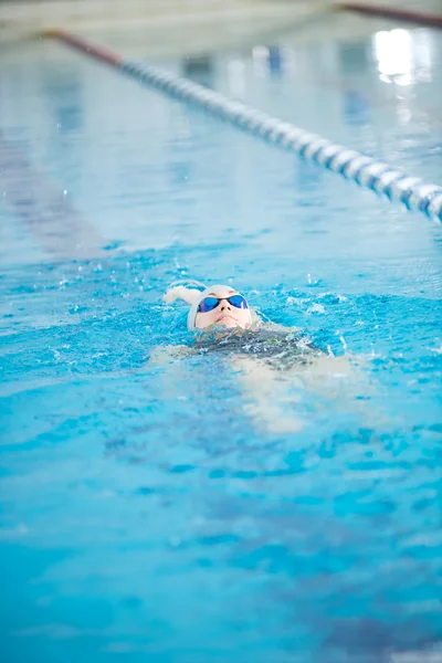 Junges Mädchen in Schutzbrille schwimmt zurück kriechen Schlaganfall Stil — Stockfoto