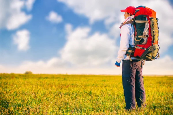 Wanderer mit Rucksack steht im Feld — Stockfoto