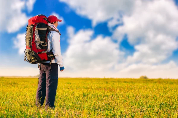 Wanderer mit Rucksack steht im Feld — Stockfoto