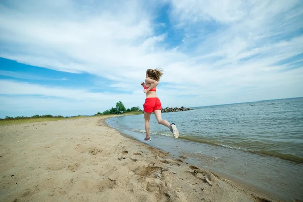 Frau läuft am Strand — Stockfoto