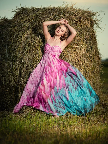 Vrouw in avond veld over hooiberg. — Stockfoto