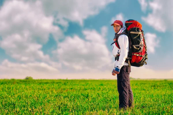 Vandrare med ryggsäck står i fältet — Stockfoto