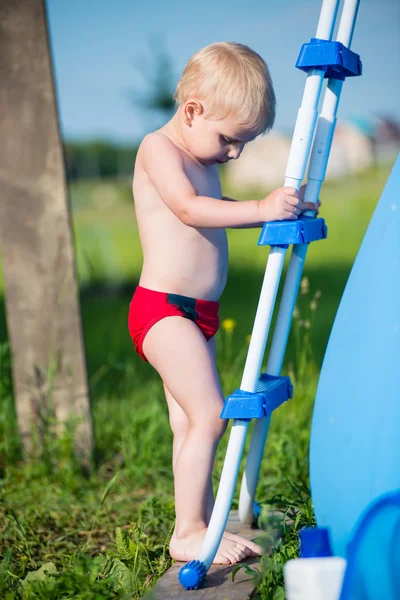 Мальчик, стоящий на лестнице бассейна — стоковое фото