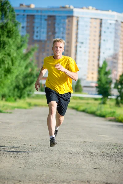 Sporty man jogging in city street park. Outdoor fitness. — Stock Photo, Image