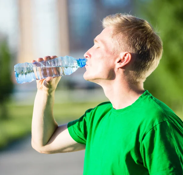 Втомлений чоловік п'є воду з пластикової пляшки після фітнесу — стокове фото