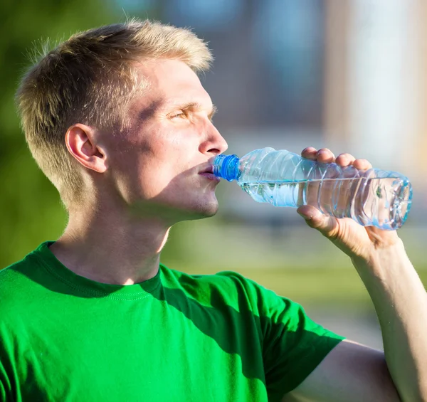 Yorgun bir adam içme suyu fitness sonra plastik bir şişe — Stok fotoğraf