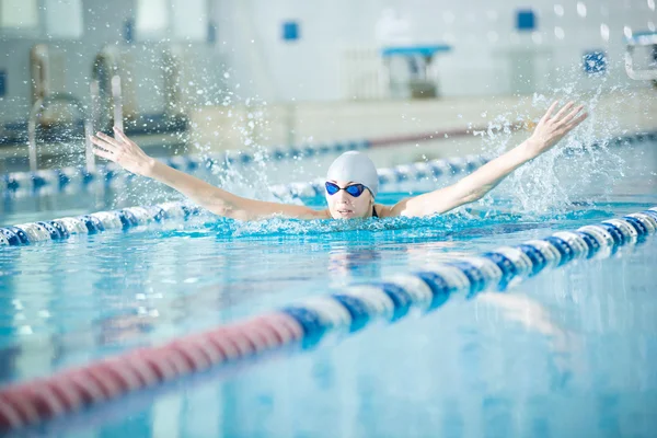 Junges Mädchen mit Brille schwimmt Schmetterlingsstreichelstil — Stockfoto