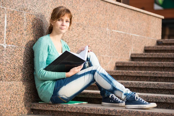 Girl sitting on stairs and reading note — Stock Photo, Image