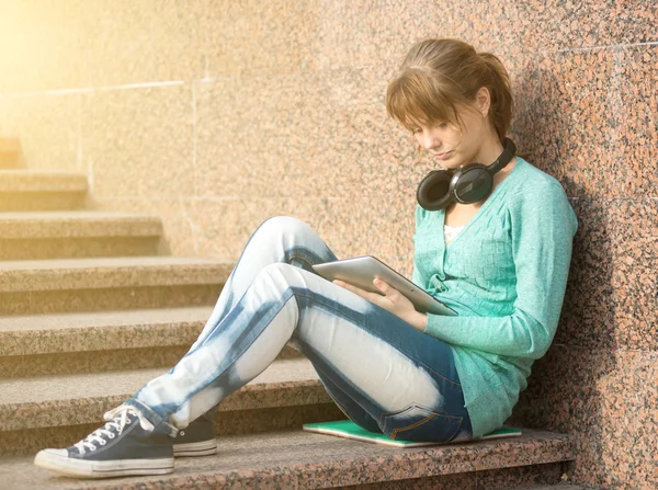 Mooie jonge vrouw student met opmerking stootkussen en hoofdtelefoon. Buiten student. — Stockfoto