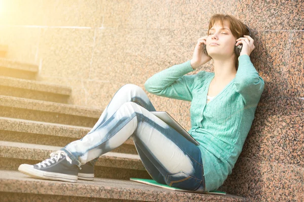 Mooie jonge vrouw student met een koptelefoon. Buiten muziek meisje — Stockfoto