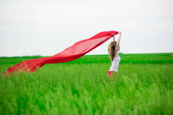 Jonge dame runing met weefsel in groene veld. Vrouw met sjaal. — Stockfoto