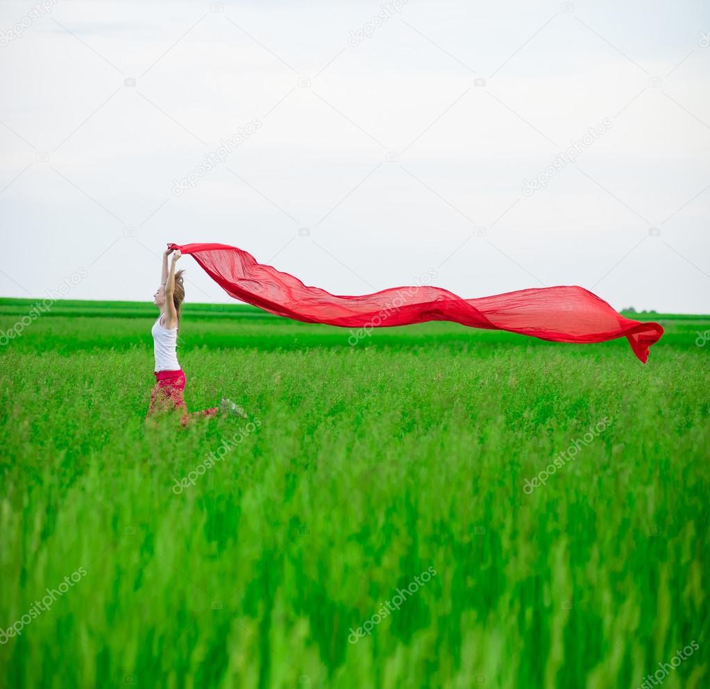 Young lady runing with tissue in green field. Woman with scarf.