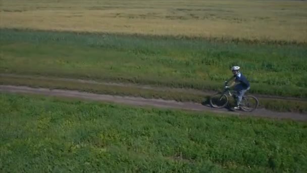Человек ездит на велосипеде по сельской дороге. Вид с воздуха . — стоковое видео