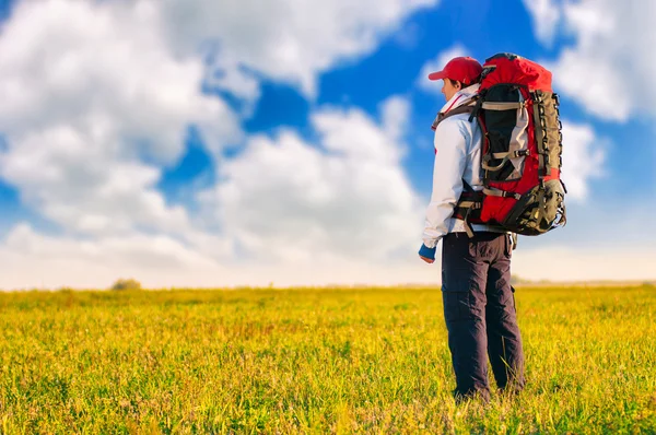 Wandelaar met rugzak staan in het veld — Stockfoto