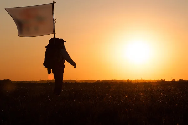 徒步旅行者背包和旗子在田里走 — 图库照片