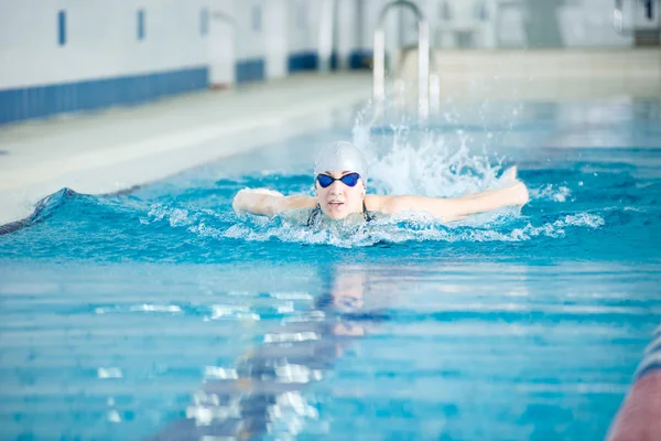 Ung flicka i glasögon simma fjärilsim stil — Stockfoto
