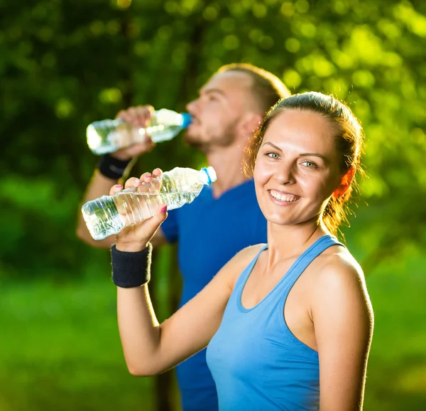 Erkek ve kadın içme suyu şişe fitness spor egzersiz sonrası — Stok fotoğraf