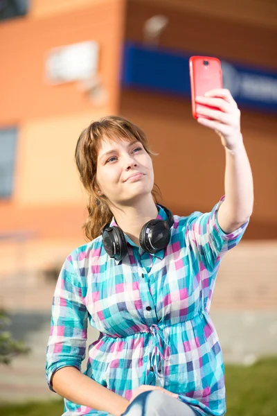 Gelukkig jonge wpman nemen van foto's van zichzelf via mobiele telefoon. Selfie. — Stockfoto