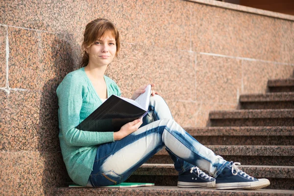 Girl sitting on stairs and reading note — Stock Photo, Image