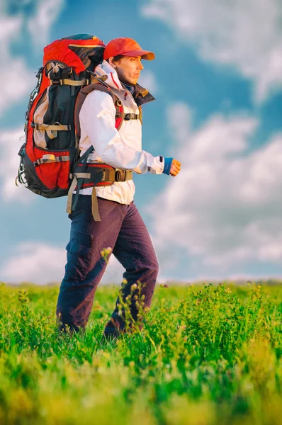 Wanderer mit Rucksack im Feld unterwegs — Stockfoto