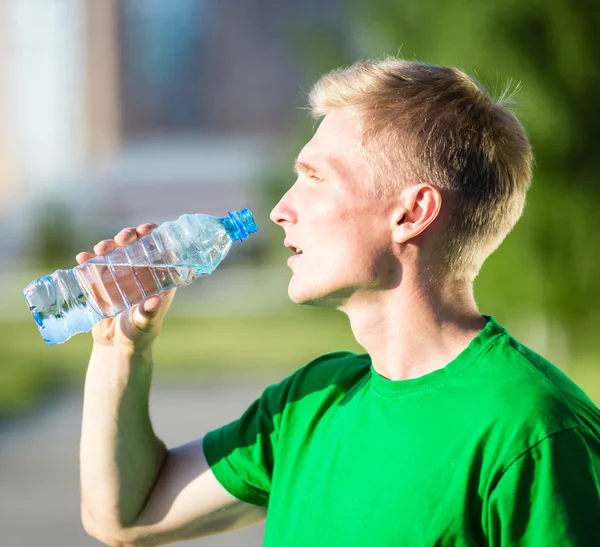 Trött man dricksvatten från en plastflaska efter fitness — Stockfoto