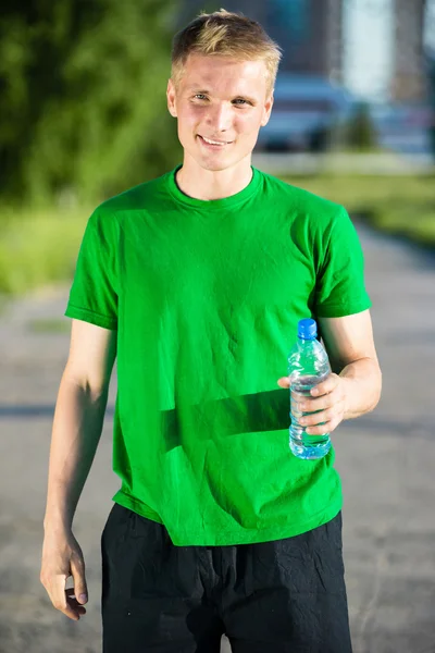 Müder Mann trinkt nach Fitness Wasser aus Plastikflasche — Stockfoto