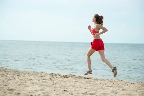 Giovane signora che corre alla soleggiata spiaggia di sabbia estiva. Allenati. Jogging — Foto Stock