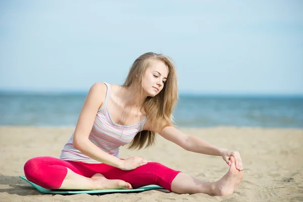 Jovencita practicando yoga. Entrenamiento cerca de la costa del mar . — Foto de Stock