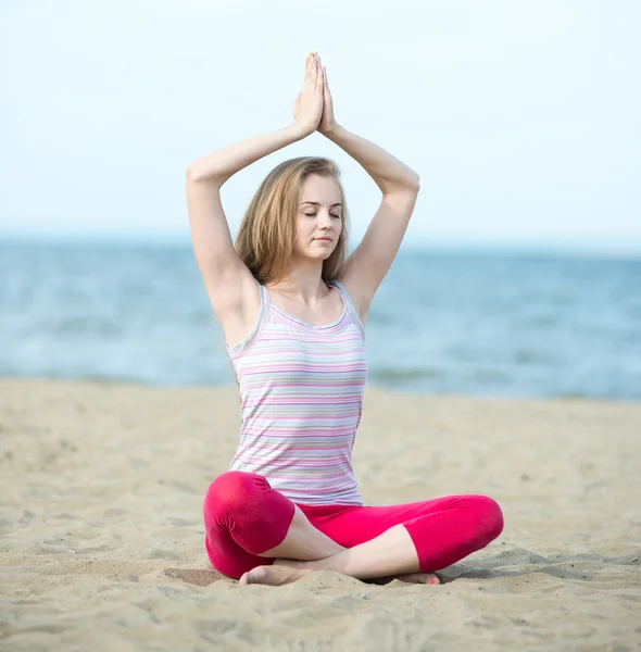 युवा महिला योग का अभ्यास करती है। समुद्र तट के पास कसरत . — स्टॉक फ़ोटो, इमेज