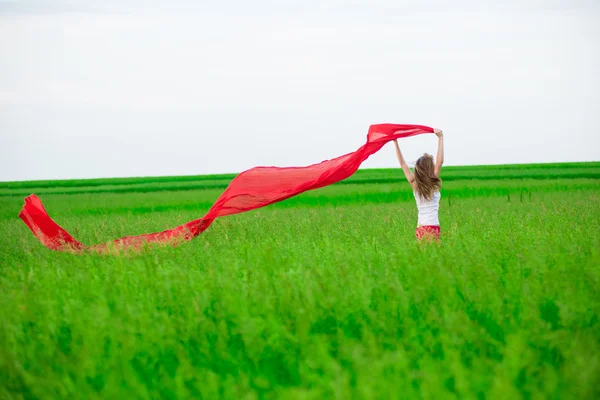 Junge Frau läuft mit Gewebe auf der grünen Wiese. — Stockfoto