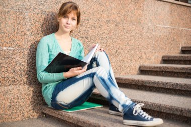 Merdivenlerde oturan ve Not okuma kız