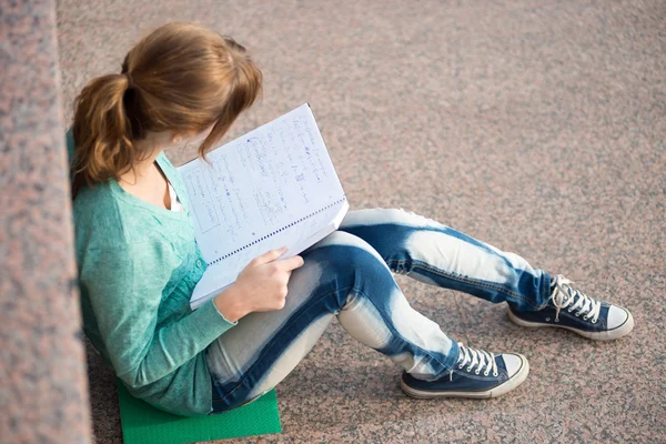 Girl sitting on stairs and reading note — Stock Photo, Image