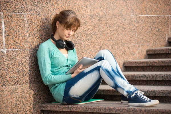 Mooie jonge vrouw student met opmerking stootkussen en hoofdtelefoon. Buiten student. — Stockfoto