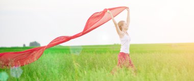 Young lady runing with tissue in green field. Woman and red scarf.