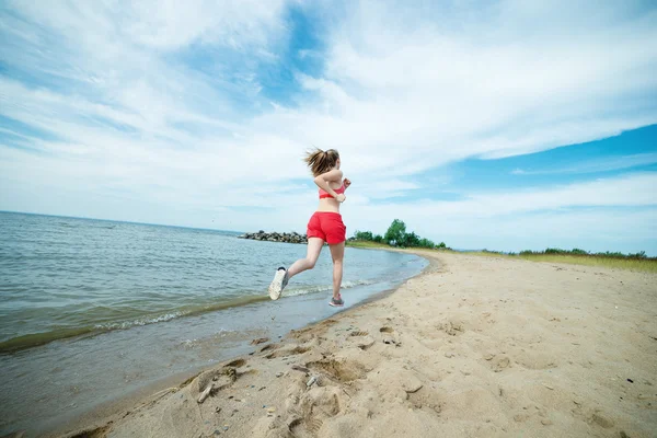 Jovencita corriendo en la soleada playa de arena de verano. Entrenamiento. Corre. — Foto de Stock