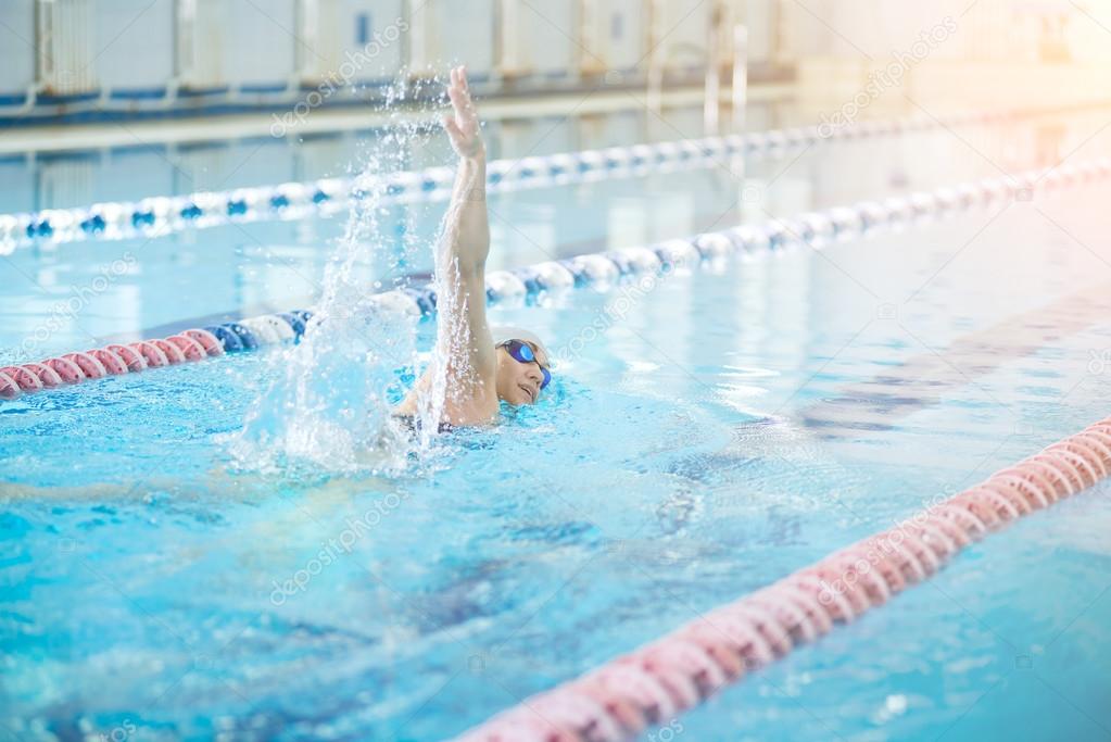 Young girl in goggles swimming front crawl stroke style