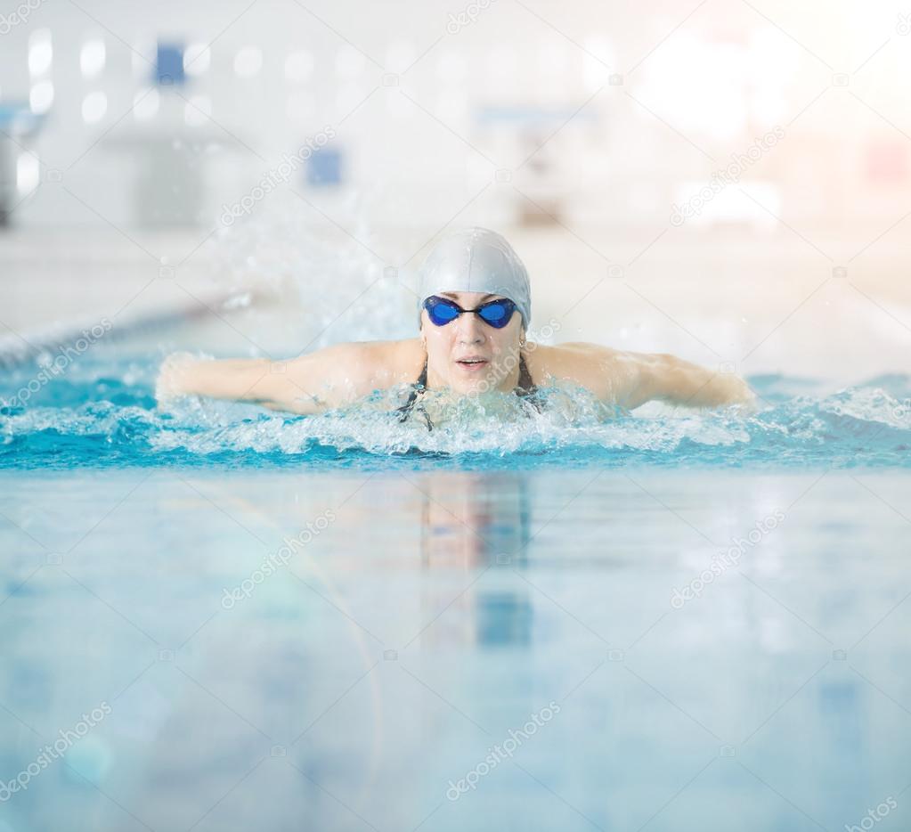 Young girl in goggles swimming butterfly stroke style