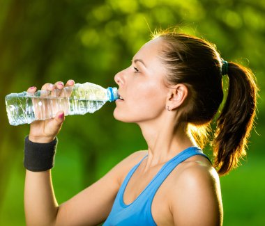Spor sonrası su içen genç bir kadın.