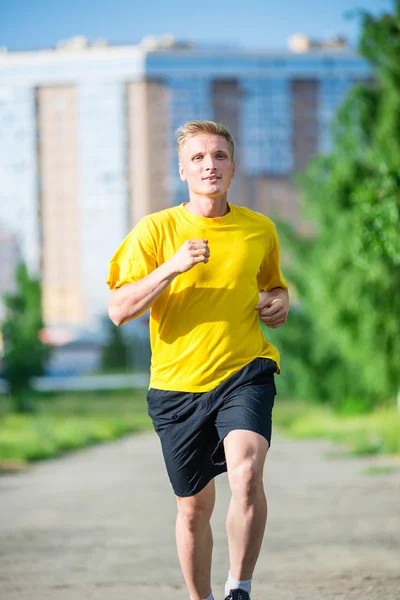 Sporty man jogging in city street park. Outdoor fitness. — Stock Photo, Image