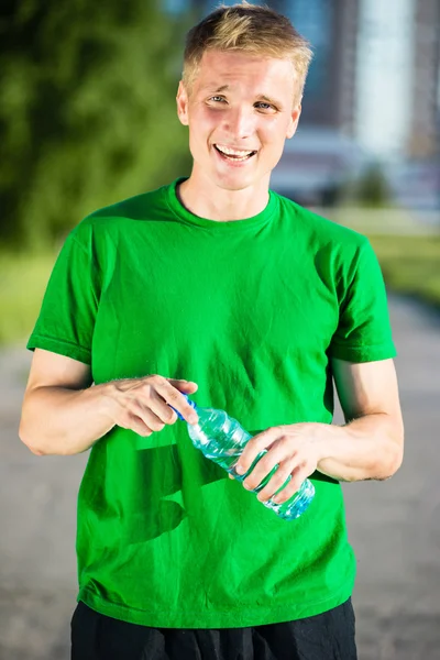 Trött man dricksvatten från en plastflaska efter fitness — Stockfoto