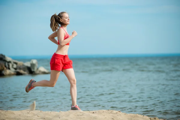 Jovencita corriendo en la soleada playa de arena de verano. Entrenamiento. Corre. —  Fotos de Stock