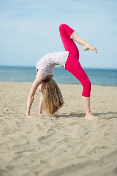 Jovencita practicando yoga. Entrenamiento cerca de la costa del mar . —  Fotos de Stock